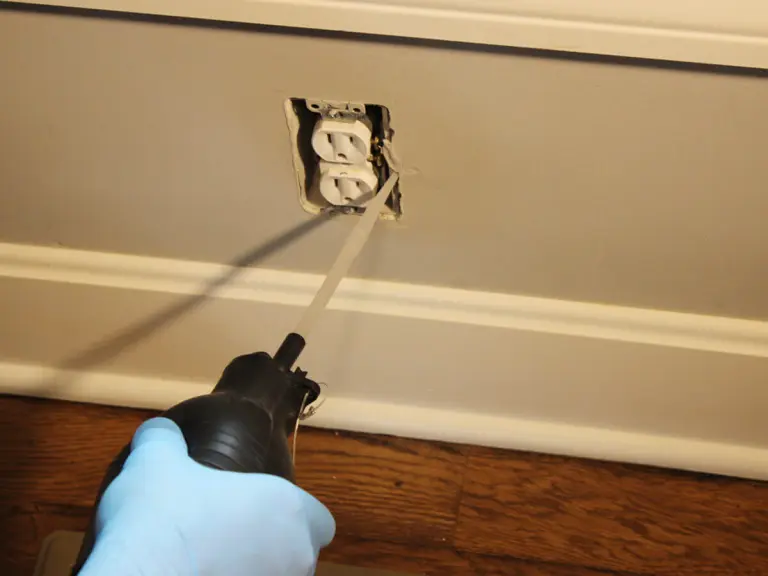 An image showing Cimexa being applied with a handheld duster into an electrical outlet